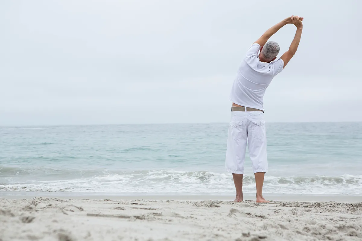 Hombre hace ejercicio en la playa mirando al mar