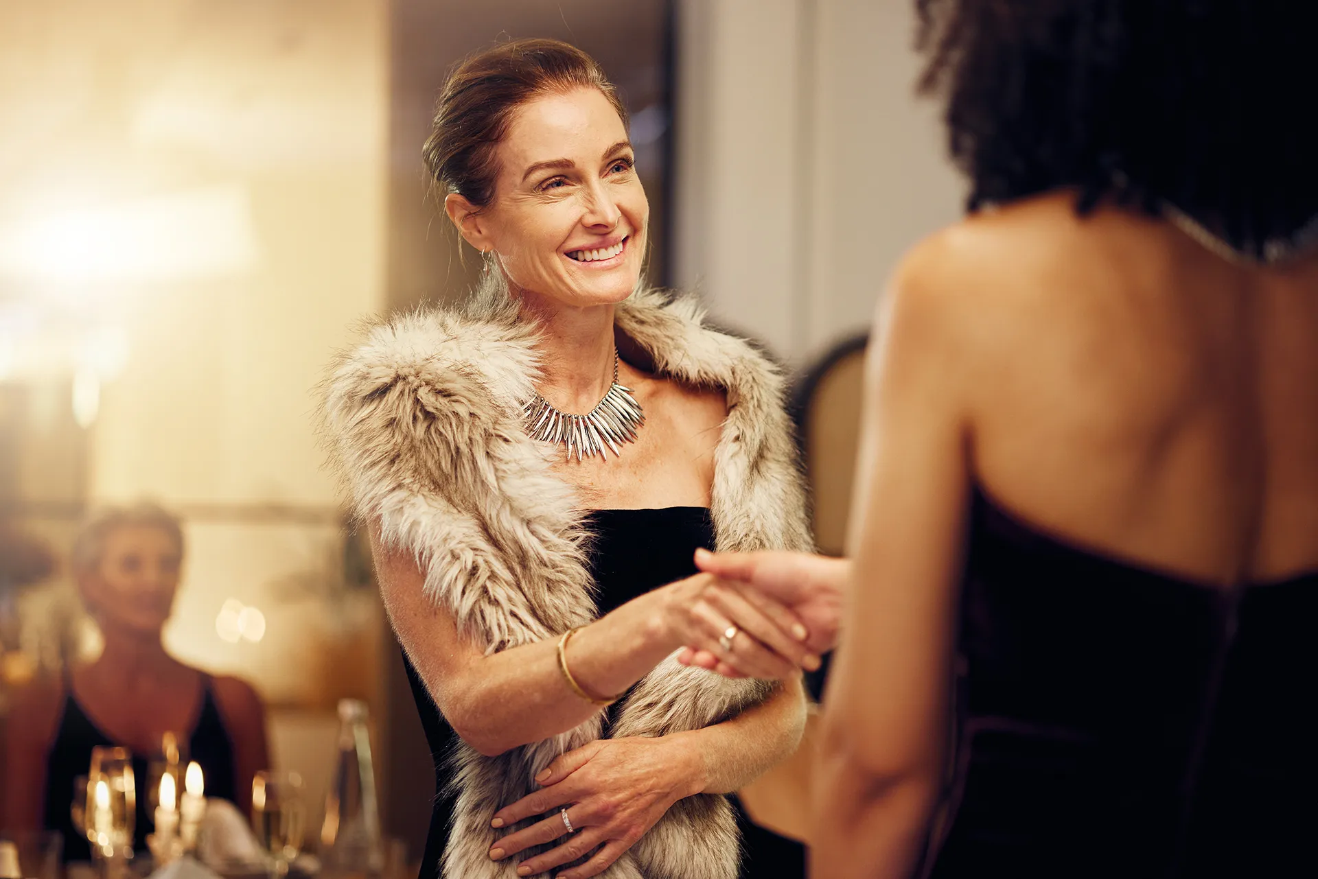 Mujeres elegantes se saludan en un cóctel