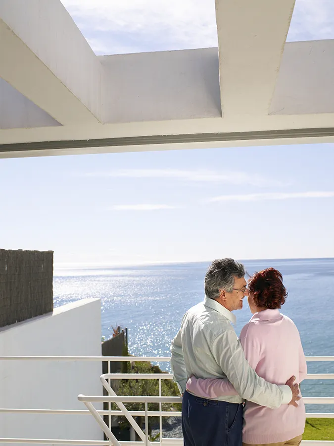 Concierge, wellness, gastronomía y servicios 24/7 One Eighty Pareja en la terraza de un apartamento frente al mar mediterráneo